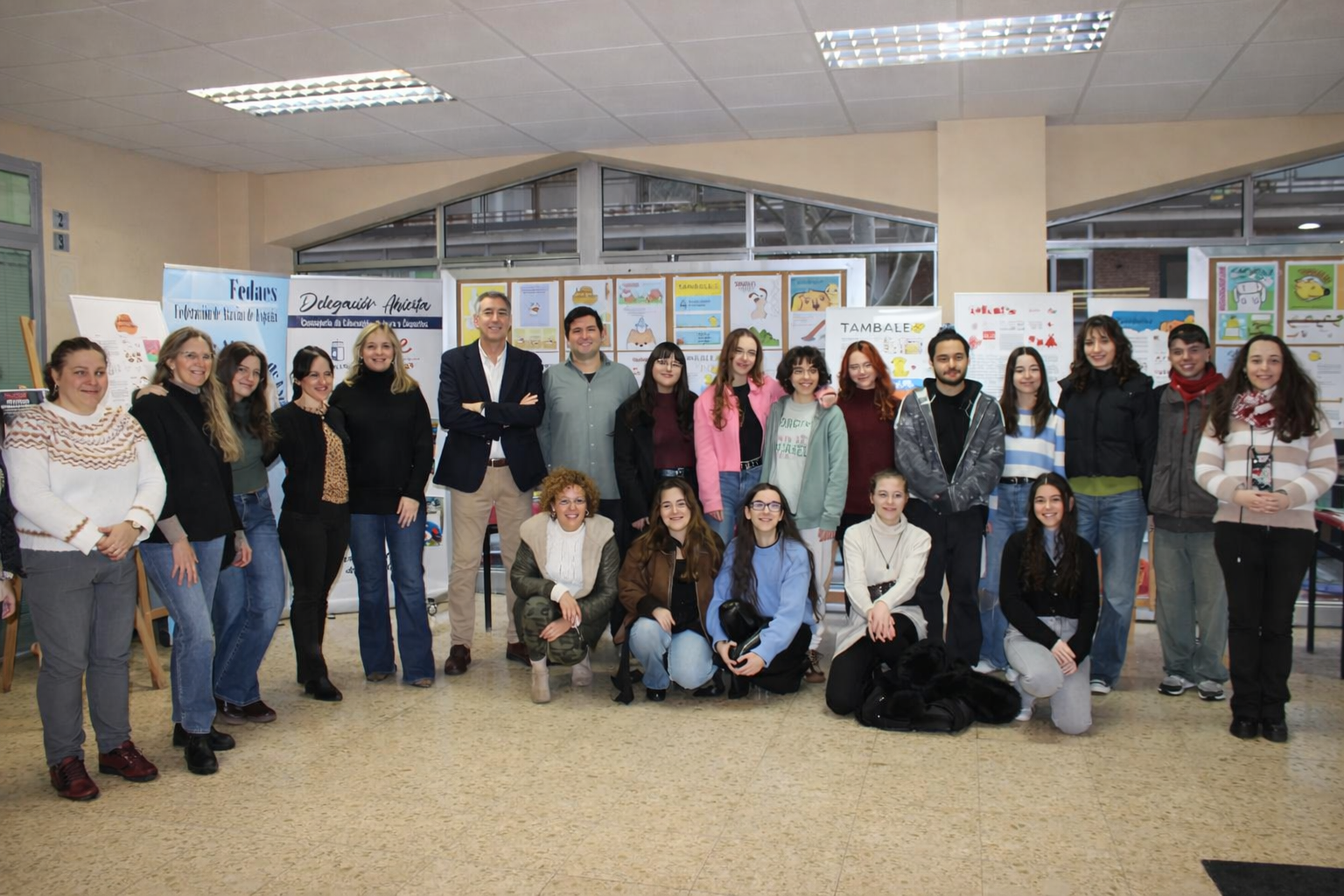 Grupo de estudiantes, Delegado de Educación y personal de la administración docentes posando juntos en un centro educativo durante una exposición de 